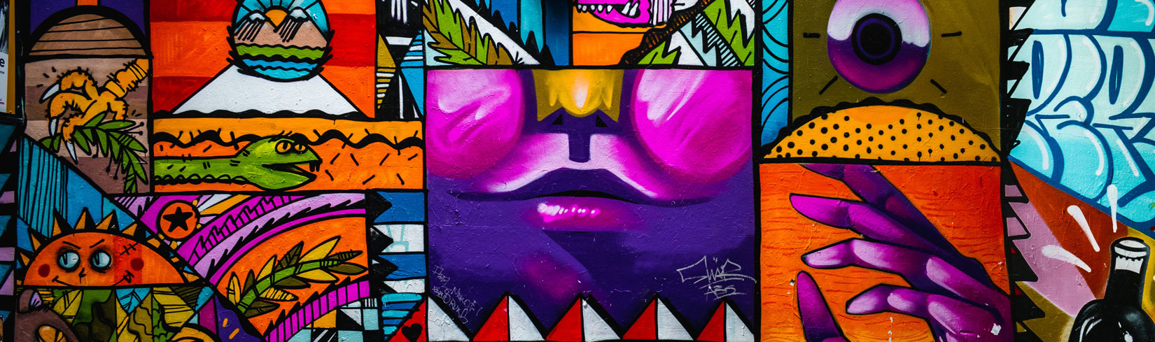 Colorful mural featuring abstract shapes, vibrant colors, and expressive faces, showcasing the artistic style of Dr. George Dagliyan, emphasizing themes of freedom and authenticity.
